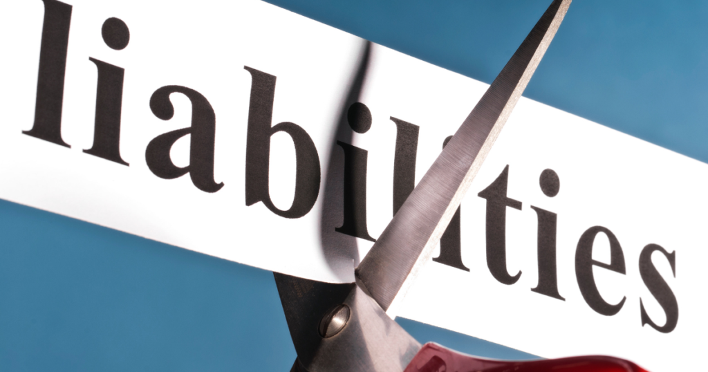 Scissors cutting a paper with the word "liabilities" printed on it.