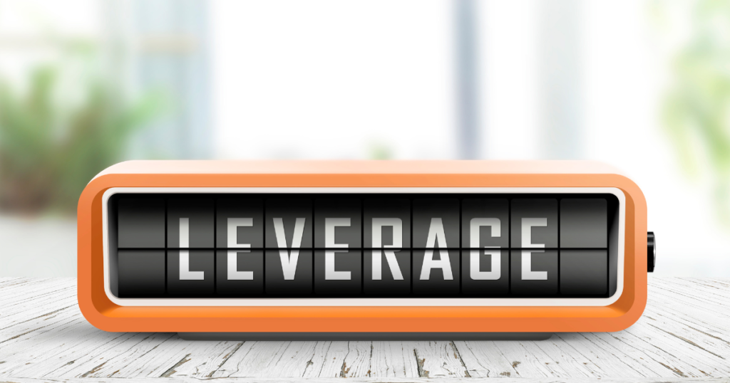 Retro-style orange digital flip clock displaying the word "LEVERAGE" on a wooden surface.